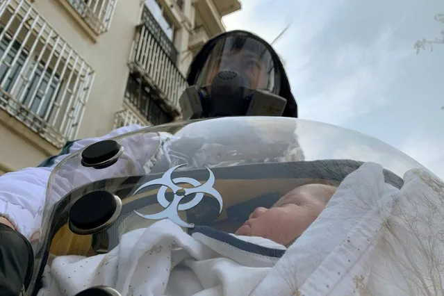 Cao Junjie poses for a picture with his two-month old baby inside a safety pod he created at a residential compound in Shanghai, China on March 25, 2020. (Photo by Xihao Jiang/Reuters)