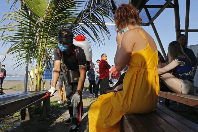 An official sprays disinfectant to prevent the new coronavirus as foreign tourists wait for their departure at a harbor in Bali, Indonesia, Sunday, March 15, 2020. For most people, the new coronavirus causes only mild or moderate symptoms, such as fever and cough. For some, especially older adults and people with existing health problems, it can cause more severe illness, including pneumonia. (Photo by Firdia Lisnawati/AP Photo)