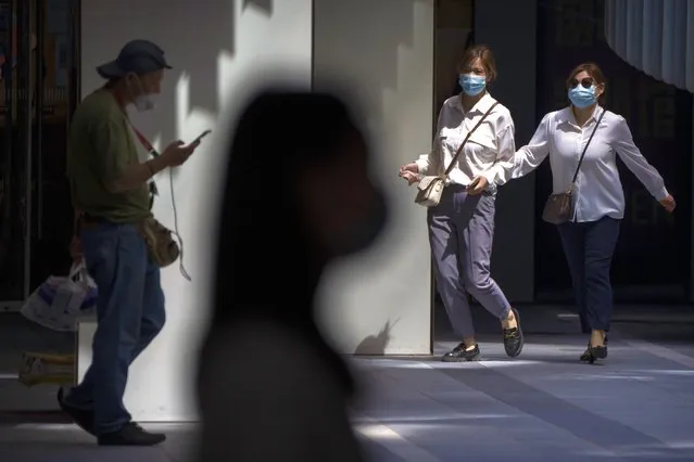 People wearing face masks walk through a shopping and office complex in Beijing, Wednesday, August 24, 2022. China is easing its tight restrictions on visas after it largely suspended issuing them to students and others more than two years ago at the start of the COVID-19 pandemic. (Photo by Mark Schiefelbein/AP Photo)