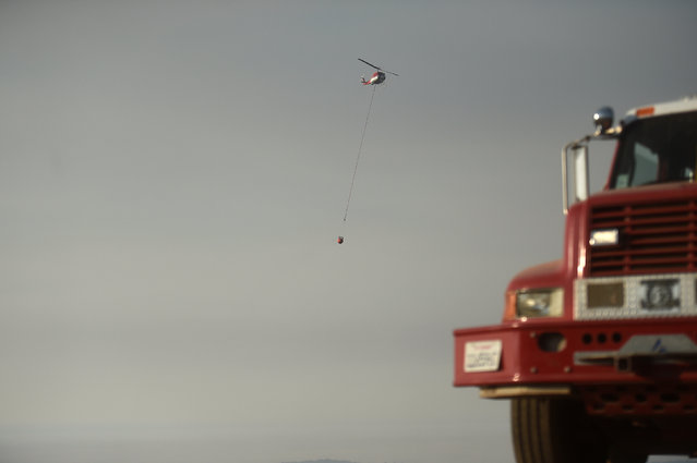 A helicopter carries water to drop on the Soberanes Fire in Carmel Highlands, California, U.S. July 27, 2016. (Photo by Noah Berger/Reuters)