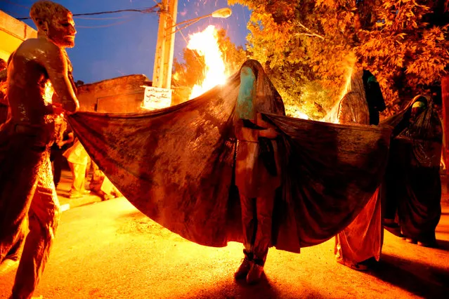 Iranian Shiite Muslim women gather around a bonfire after rubbing mud on their body during the “Kharrah Mali” (Mud Rubbing) ritual to mark the Ashura religious ceremony in the city of Khorramabad, some 470 kms southwest of Tehran, early in the morning on October 1, 2017. “Khrreh Mali” or “Mud Rubbing” is a ritual that is held in the city of Khorramabad every year to commemorate the seventh century slaying of Prophet Mohammed' s grandson Imam Hussein, in which Iranian men roll over in mud and dry themselves by gathering around the bonfires before flagellating themselves. (Photo by Atta Kenare/AFP Photo)