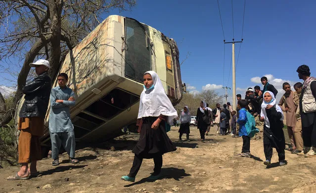 School children pass by a bus that was transporting education ministry officers to work as it was hit by a road side bomb on the outskirts of Kabul, Afghanistan, 11 April 2016. At least one employee of the Afghan Ministry of Education was killed and seven others injured in a blast in Kabul on 11 April 2016. (Photo by Jawad Jalali/EPA)