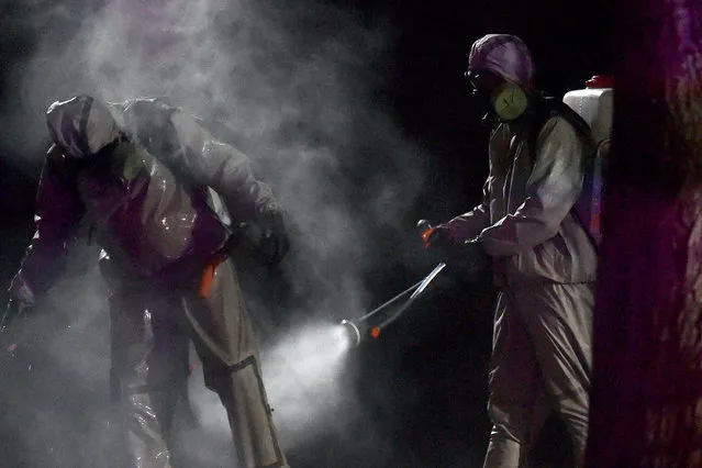 Belarus' servicemen wearing protective gear spray disinfectant on each other after sanitizing a hospital in the town of Zaslauye, outside Minsk, on April 29, 2020, amid the coronavirus pandemic. (Photo by Sergei Gapon/AFP Photo)