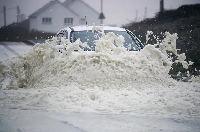 A car drives through sea foam whipped up by the wind of Hurricane Ophelia at Trearddur Bay on October 16, 2017 in Holyhead, Wales. Hurricane Ophelia comes exactly 30 years after the Great Storm of 1987. Two people have been killed as the remnants of the storm hit the United Kingdom and Ireland. (Photo by Christopher Furlong/Getty Images)