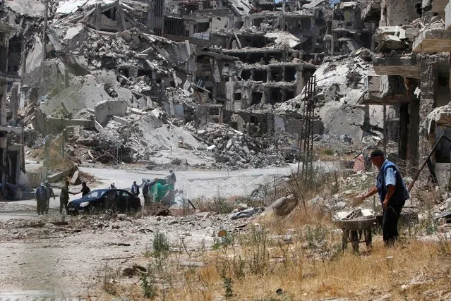 Workers collect the rubble of damaged buildings to be recycled and reused for reconstruction, under the supervision of the United Nations Development Programme (UNDP) in the government-controlled district of Wadi al-Sayeh in Homs, Syria July 19, 2016. (Photo by Omar Sanadiki/Reuters)