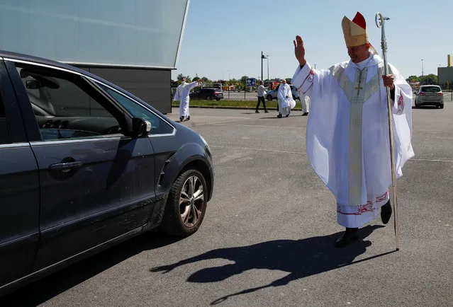 French archbishop of Chalons-en-Champagne Francois Touvet waves to people after France's first ever drive-in mass in Chalons en Champagne, after the country began a gradual end to the nationwide lockdown following the coronavirus disease (COVID-19) outbreak, near Reims, France, May 17, 2020. (Photo by Gonzalo Fuentes/Reuters)