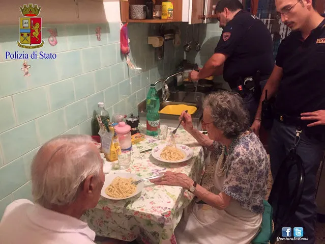 In this recent photo made available by the Italian Police, two police officers serve pasta, after cooking it, to two elderly, after they were called in a Rome neighborhood to check on a couple loudly quarreling on a recent, hot summer night. Police say that four officers who came to the couple's apartment used butter, cheese, spaghetti and “all their humanity” to cook them dinner and ease their loneliness. (Photo by Italian Police Photo via AP Photo)