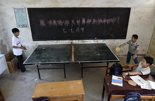Students play table tennis inside a classroom of Dalu primary school in Gucheng township of Hefei, Anhui province, China, September 8, 2015. The Chinese characters on the blackboard read, “Celebrate the 70th anniversary of the victory of Chinese People's War of Resistance Against Japanese Aggression”. (Photo by Reuters/Stringer)