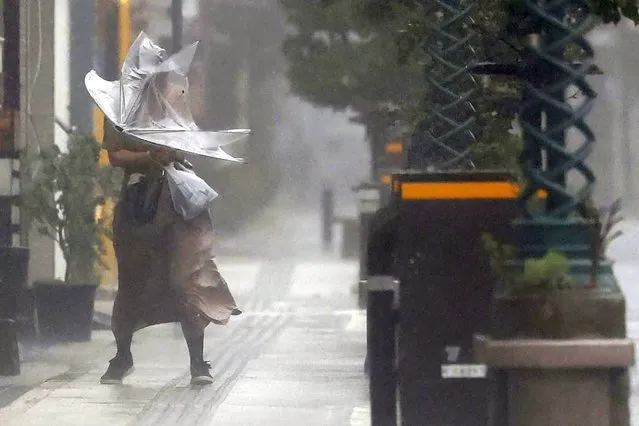 A woman makes her way through the strong wind and rain in Miyazaki, southern Japan, Sunday, September 18, 2022, as a powerful typhoon pounded southern Japan. (Photo by Kyodo News via AP Photo)