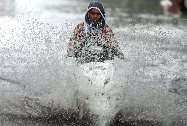 A person rides a scooter through a waterlogged road during monsoon rain showers in Mumbai, India, June 4, 2020. (Photo by Francis Mascarenhas/Reuters)