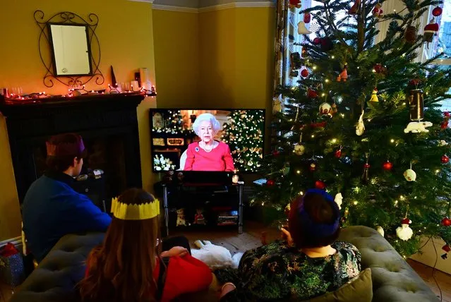 A family watch as Britain's Queen Elizabeth II delivers her annual Christmas Broadcast message, at their home near Liverpool on December 25, 2021. Queen Elizabeth II paid a touching tribute to her late husband Prince Philip in her Christmas Day message as she marked the holiday with a family gathering. (Photo by Paul Ellis/AFP Photo)