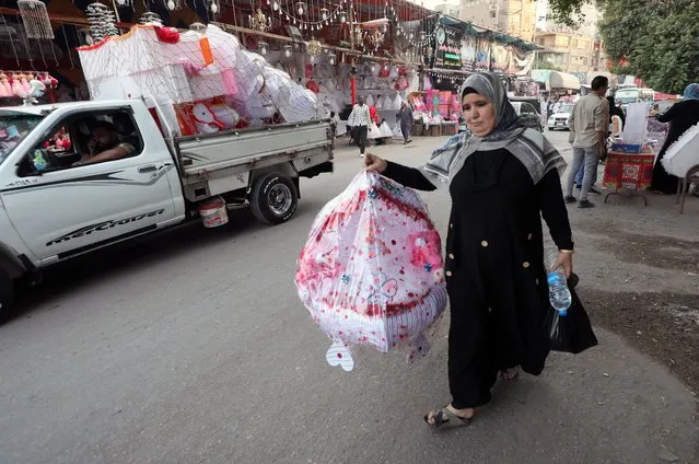An Egyptian woman carries a candy doll for the upcoming Mawlid celebrations (The birthday of Prophet Muhammad), at a local market in Sayeda Zienab district, in Cairo, Egypt, 05 October 2022. Prophet Muhammad's birthday will be marked on 08 October this year. The decoration of candy dolls for this occasion is believed to date back to the time of the Fatimid dynasty's (909–1171) rule in Egypt. (Photo by Khaled Elfiqi/EPA/EFE)