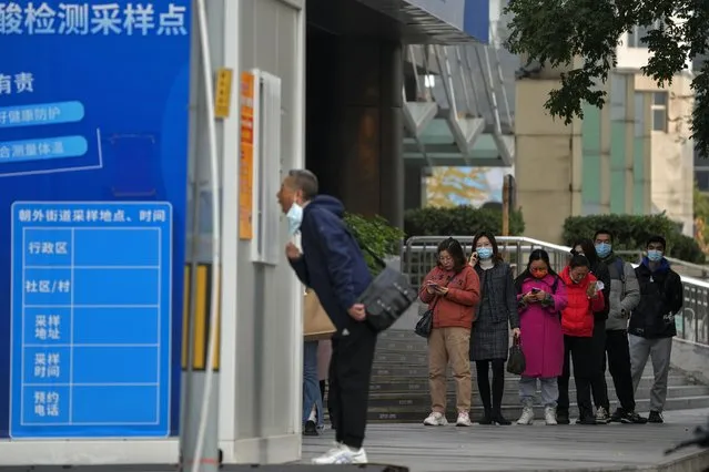 People wait in line for their routine COVID-19 throat swabs at a coronavirus testing site setup along a pedestrian walkway in Beijing, Wednesday, November 2, 2022. (Photo by Andy Wong/AP Photo)