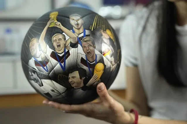 Paraguayan artist Lili Cantero holds a hand-painted soccer ball illustrated with members of the Germany squad for 2014 World Cup, in San Lorenzo, Paraguay, Thursday, November 10, 2022. Decoratively detailing the lavish stadiums of the upcoming tournament in Qatar – the first to take place in the Middle East – as well as the most sought after players and teams, Cantero is preparing the last details of her soccer-inspired art show, “8 Stadiums, 8 Champions, 1 Dream: Qatar 2022”. (Photo by Jorge Saenz/AP Photo)