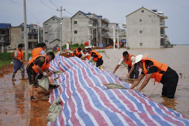 In this photo released by Xinhua News Agency, workers build a dyke to stop flood waters at Jiangjialing village of Poyang County in eastern China's Jiangxi province Saturday, July 11, 2020. Chinese authorities forecasted heavy rain across a wide swath of the country prompting evacuation of residents and raising emergency alerts levels. (Photo by Zhang Haobo/Xinhua via AP Photo)