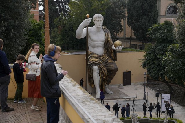 Visitors admire a massive, 13-meter (yard) replica of the statue Roman Emperor Constantine commissioned for himself after 312 AD that was built using 3D technology from scans of the nine giant original marble body parts that remain, as it was unveiled in Rome, Tuesday, February 6, 2024. The imposing figure of a seated emperor, draped in a gilded tunic and holding a scepter and orb, gazing out over his Rome, is located in a side garden of the Capitoline Museums, just around the corner from the courtyard where the original fragments of Constantine's giant feet, hands and head are prime tourist attractions. (Photo by Andrew Medichini/AP Photo)