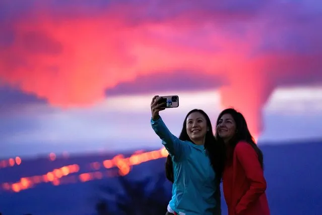 Ingrid Yang, left, and Kelly Bruno, both of San Diego, take a photo in front of lava erupting from Hawaii's Mauna Loa volcano Wednesday, November 30, 2022, near Hilo, Hawaii. (Photo by Gregory Bull/AP Photo)