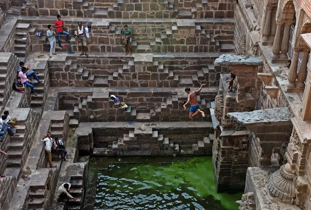 An Indian youth jumps into the water of the historic Chand Baori stepwell as others look on in Abhaneri village of western Rajasthan state on September 24, 2015. For a few hours on one day each year, local residents are permitted to descend into the 100-foot-deep, 1,200-year-old stepwell, as Hindu devotees in the area mark a local festival, at the same time as Hindus worldwide observe Ganesh Chaturthi festivities. (Photo by Alex Ogle/AFP Photo)