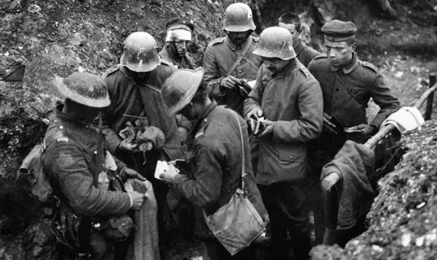 British troops sort through the belongings of German prisoners in a trench, with articles being placed in an empty sand bag, 1916. (Photo by EMPICS Sports Photo Agency)