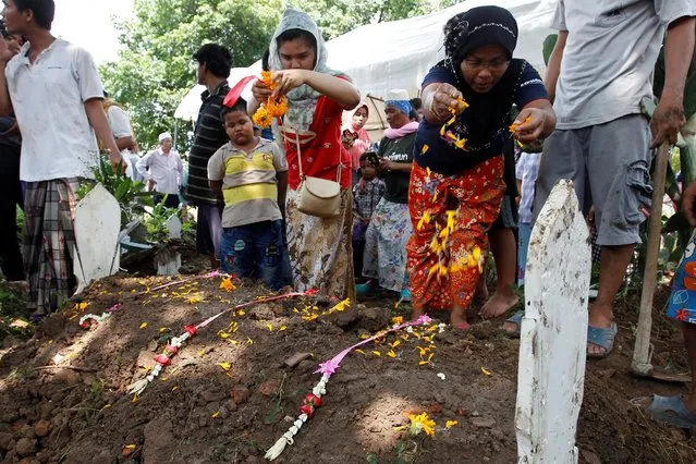 Relatives of a victim of a capsized boat on the Chao Phraya river, decorate a grave during a funeral at a graveyard in the ancient tourist city of Ayutthaya, Thailand September 19, 2016. (Photo by Chaiwat Subprasom/Reuters)
