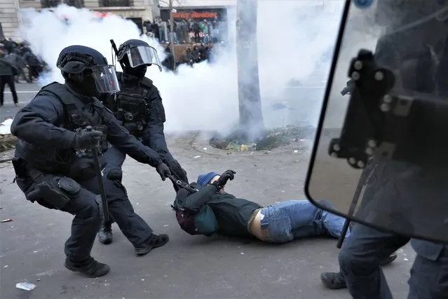 Riot police officers grab a protestor during a demonstration against pension changes, Thursday, January 19, 2023 in Paris. Workers in many French cities took to the streets Thursday to reject proposed pension changes that would push back the retirement age, amid a day of nationwide strikes and protests seen as a major test for Emmanuel Macron and his presidency. (Photo by Lewis Joly/AP Photo)