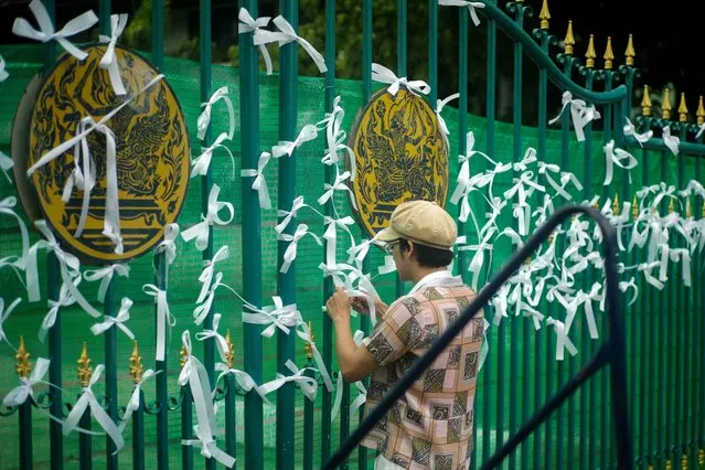 A pro-democracy protester ties white ribbons at the gate of Remand Prison to call for the release of Anon Nampa and Panupong Jadnok, in Bangkok, Thailand, September 4, 2020. (Photo by Panu Wongcha-um/Reuters)