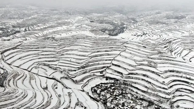 This aerial photo taken on February 8, 2023 shows terraced fields and houses after a snowfall in Longnan, in China's northwestern Gansu province. (Photo by AFP Photo/China Stringer Network)