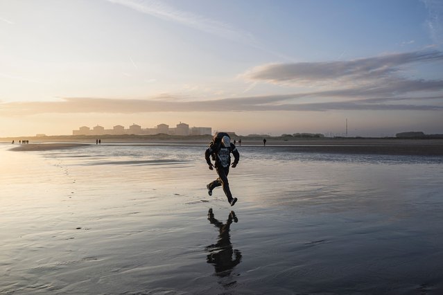 A migrant runs to board a smuggler's inflatable dinghy in an attempt to cross the English Channel off the beach of Gravelines, northern France on July 29, 2025. (Photo by Sameer Al-Doumy/AFP Photo)