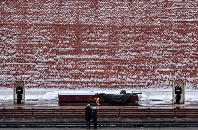 People look at the Eternal Flame and the Unknown Soldier's Grave at the Kremlin wall in the Alexander Garden in Moscow on March 14, 2023. (Photo by Yuri Kadobnov/AFP Photo)