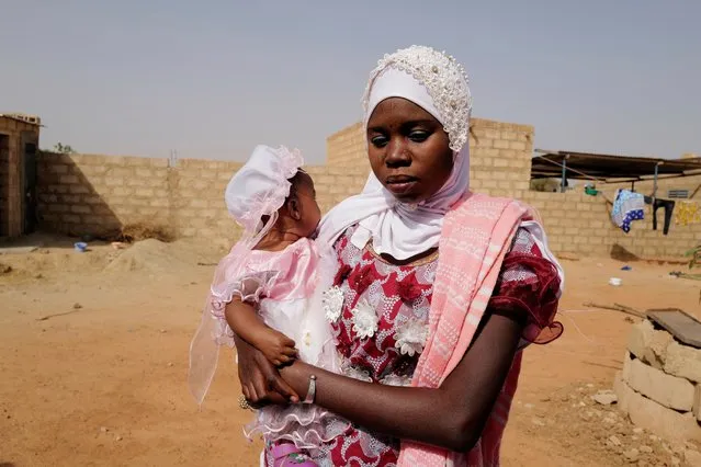 Maiga Radiatou, 21, who fled from attacks of armed militants in Sahel region of Soum and who will not be able to vote in Burkina Faso's presidential election on Sunday carries her seven months daughter Sameuna as she stands at a courtyard of the house in an informal camp for displaced people on the outskirts of Ouagadougou, Burkina Faso on November 19, 2020. (Photo by Zohra Bensemra/Reuters)