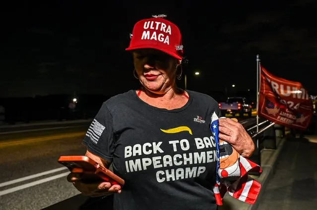 Supporters of former US President Donald Trump listen on the phone to his speech outside Mar-a-Lago estate in Palm Beach, Florida, on April 4, 2023. (Photo by Giorgio Viera/AFP Photo)