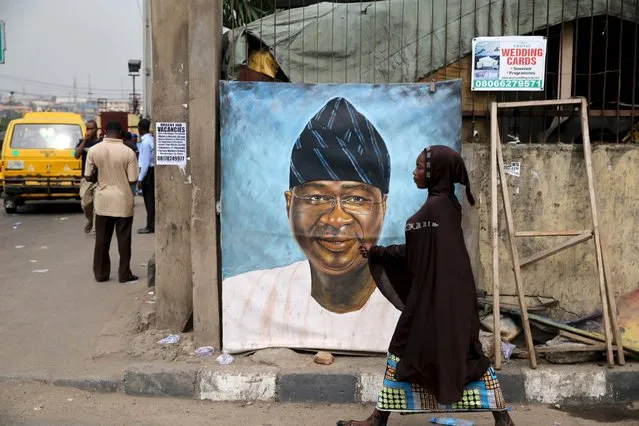 A woman walks past a portrait of Nigeria's new Power, Works and Housing Minister Babatunde Fashola along a road in Ikeja district in Lagos Nivember 16, 2015. (Photo by Akintunde Akinleye/Reuters)