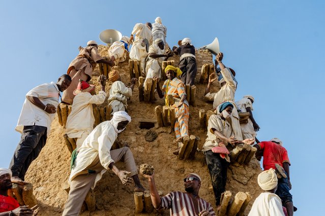 Residents climb up the wall with mud in their hands during the annual replaster of the Djinguereber Mosque, also known as Djingareyber or Djingarey Ber, in Timbuktu on October 12, 2025. The 2025 replaster marks the 700th anniversary of the construction of this mosque, erected in the 14th century during the reign of Emperor Kankou Moussa. (Photo by Hameye Capii/AFP Photo)