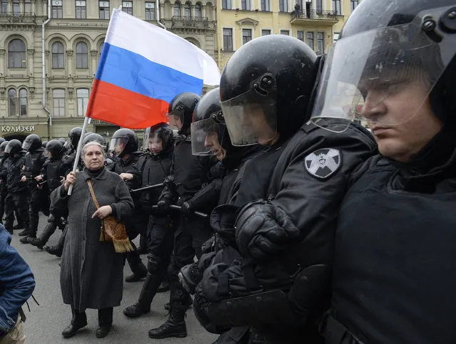 A woman holding a Russian flag stands in front of riot police blocking an area during an unauthorized anti-Putin rally called by opposition leader Alexei Navalny on May 5, 2018 in Saint Petersburg, two days ahead of Vladimir Putin's inauguration for a fourth Kremlin term. (Photo by Olga Maltseva/AFP Photo)