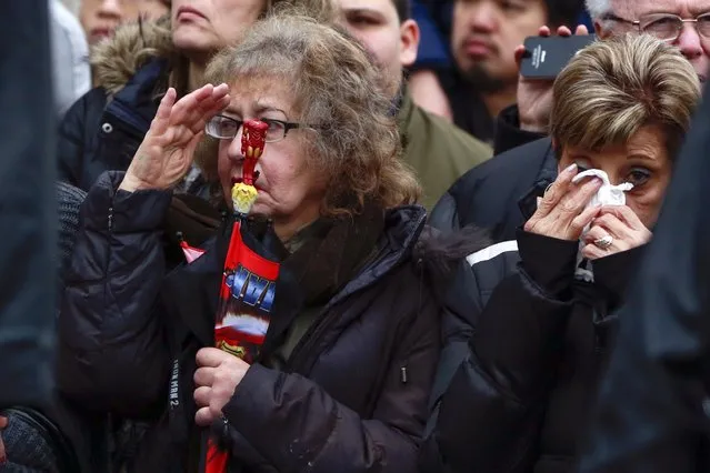 A woman salutes as another wipes tears from her eyes along the funeral procession route for NYPD officer Wenjian Liu in the Brooklyn borough of New York January 4, 2015. (Photo by Shannon Stapleton/Reuters)