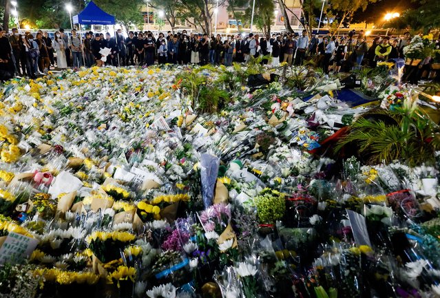 People gather next to a pile of flowers at a makeshift memorial near the Wang Fuk Court housing complex residents after the deadly fire, in Tai Po, Hong Kong, China, on December 1, 2025. (Photo by Maxim Shemetov/Reuters)