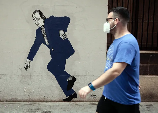 A person walks past graffiti by arstist selfnamed El Primo de Bansky (the cousin of Bansky) of former Spanish King Juan Carlos in Valencia, Spain, 05 August 2020. The Spanish Royal Household has announced that Emeritus King Juan Carlos I has proclaimed his intended decision to move abroad so as to not interfere in the image of the Spanish monarchy due to his alleged implication in a Swiss offshore account investigation. (Photo by Biel Aliño/EPA/EFE)