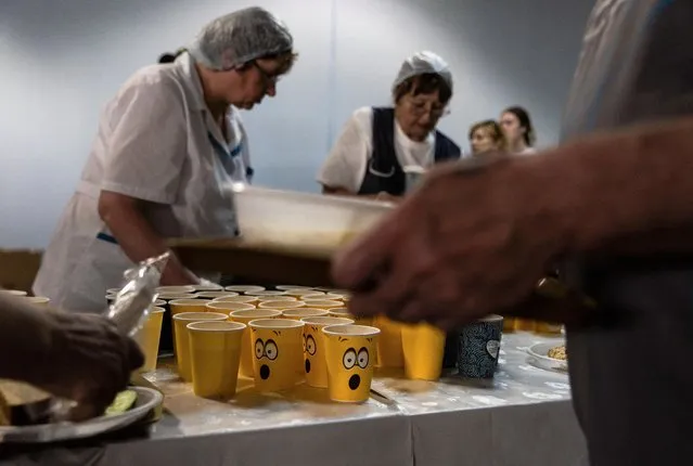 Residents of the Shebekinsky district of Russia's Belgorod region, who were evacuated following recent attacks on settlements near the Russia-Ukraine border in the course of a military conflict, queue to receive their meals at a temporary accommodation centre located in a sports facility in the city of Belgorod, Russia on June 7, 2023. (Photo by Maxim Shemetov/Reuters)