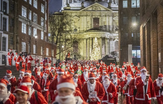 Participants wearing Santa Claus costumes outside St. Paul's Cathedral take part in a 4.5 km Santa Dash in central London on a rainy evening on December 5, 2024. (Photo by Marcin Nowak/London News Pictures)