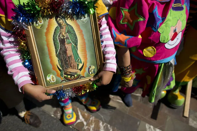 A clown carries a picture of the Virgin of Guadalupe, as she waits to enter the Basilica of Our Lady of Guadalupe in Mexico City, Monday, December 14, 2015. (Photo by Rebecca Blackwell/AP Photo)