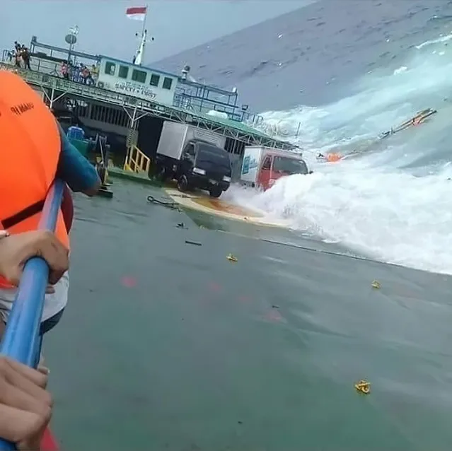 This handout picture taken and released on July 3, 2018 by Indonesia' s Badan Nasional Penanggulangan Bencana (BNPB), the accident mitigation agency, shows passengers clinging to the side of a ferry as it sank off the coast of Selayar island, in South Sulawesi province. Six people died on July 3 after a ferry sank off the coast of Indonesia, as rescuers raced to save more than 130 other passengers aboard the downed vessel, officials said. The deadly accident comes as Indonesia on July 3 officially called off a search for some 164 people still missing after another ferry sank on a lake in Sumatra two weeks ago. (Photo by AFP Photo/Badan Nasional Penanggulangan Bencana)