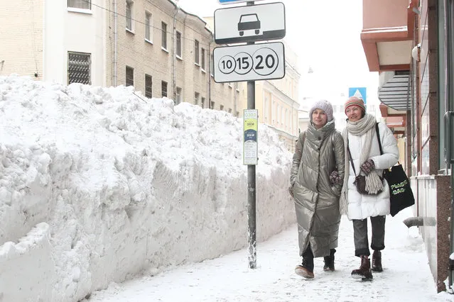 Women walk past banks of snow on Bolshaya Nikitskaya Street in central Moscow, Russia on February 14, 2021. (Photo by Valery Sharifulin/TASS)