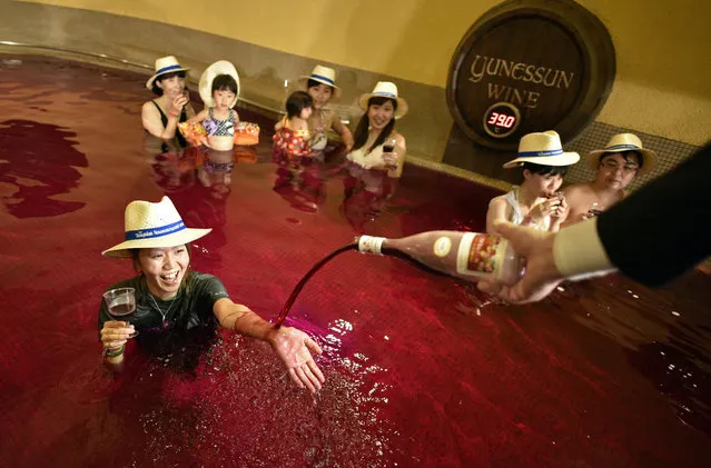 A man pours 2016 Beaujolais Nouveau wine on the hand of a woman in a colored hot water “wine bath” at Hakone Kowakien Yunessun hot spring resort in Hakone, Kanagawa prefecture, west of Tokyo, Japan, 17 November 2016, on the day of the Beaujolais Nouveau official release. With Germany and the United States, Japan is a major market for the Beaujolais Nouveau. (Photo by Franck Robichon/EPA)
