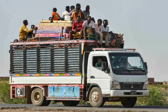 People ride with furniture and other items atop a truck moving along a road from Khartoum to Wad Madani at the locality of Kamlin, about 80 kilometres southeast of Khartoum, on June 22, 2023. (Photo by AFP Photo/Stringer)