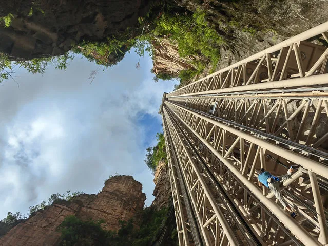 A French rock climber named Jean Michel Casanova scales the 172-meter-high steel derrick of the Bailong Elevator, also known as Bailong Sky Ladder, with his bare hands at the Wulingyuan Scenic Area on June 28, 2023 in Zhangjiajie, Hunan Province of China. (Photo by Deng Daoli/VCG via Getty Images)