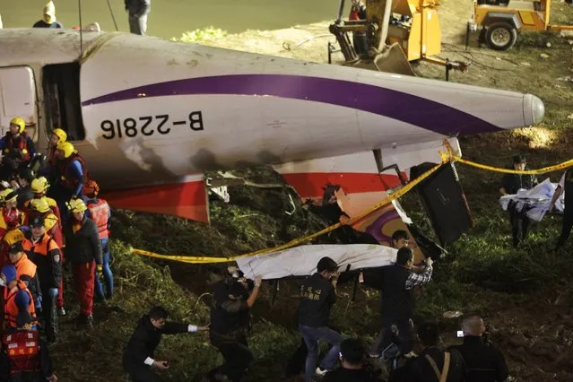 Rescuers carry one body in a bag away after a TransAsia Airways plane crash landed in a river, in New Taipei City, February 4, 2015. (Photo by Pichi Chuang/Reuters)
