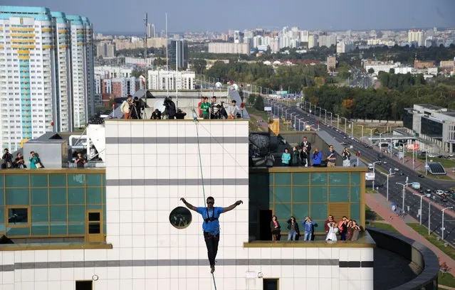 Ukrainian slackliner Stanislav Panyuta balances as he walks on a highline from the rooftop of a building in Minsk on September 23, 2015. (Photo by Sergei Gapon/AFP Photo)