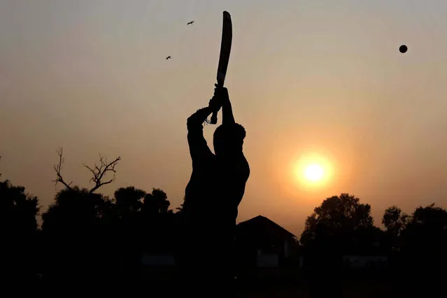 A boy is silhouetted against the setting sun as he plays cricket  in Peshawar, Pakistan, 01 March 2021. (Photo by Arshad Arbab/EPA/EFE)