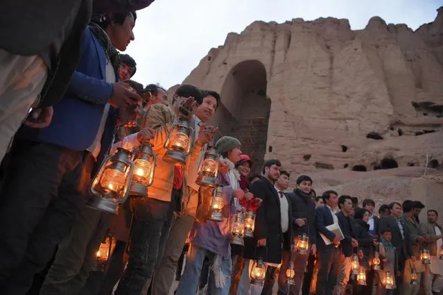 Residents and civil society activists hold lamps as they stand near the site where the Salsal Buddha statue once stood during a 20th anniversary commemoration ceremony since the destruction of the Buddhas of Bamiyan statues by the Taliban in March 2001, in Bamiyan province on March 9, 2021. (Photo by Wakil Kohsar/AFP Photo)