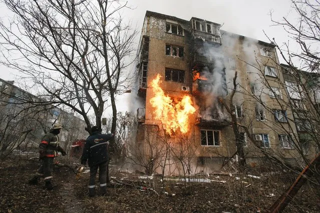 A firefighter (L) walks to the front of a residential block that has been set on fire, caused by a recent shelling according to locals, as his colleagues arrive to extinguish the fire on the outskirts of Donetsk, eastern Ukraine February 9, 2015. (Photo by Maxim Shemetov/Reuters)